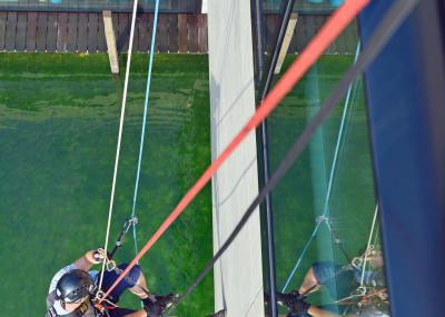 Glasreinigung am Seil in der Höhe, Gebäudereinigung mit Fassadenkletterer und Arbeit am Seil