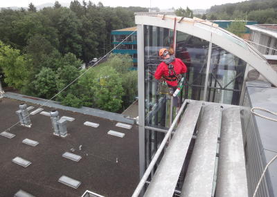 Fassadenkletterer reinigt Glasfront am hängenden Seil, Seilarbeit