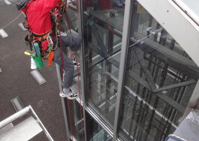 Fassadenkletterer reinigt Glasfront am hängenden Seil, Arbeit am Seil