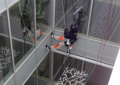 Fassadenkletterer bei Glasreinigung am hängenden Seil, in Lichtschacht